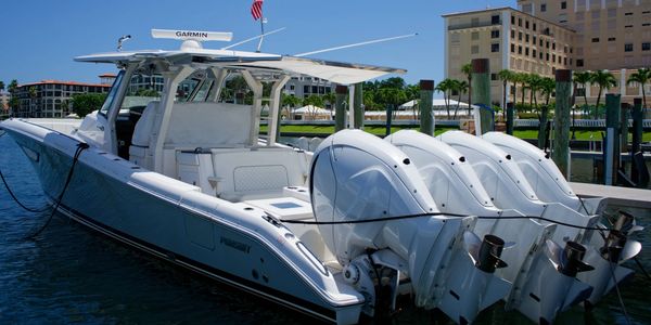 White motorboat docked with four outboard engines.