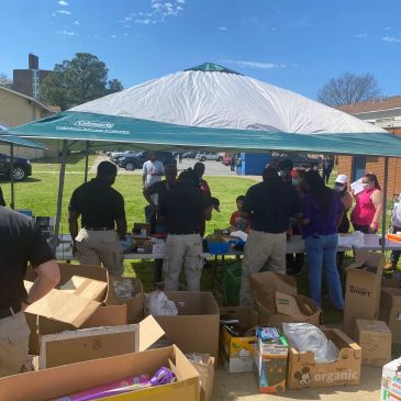 Community group distributing supplies under a canopy tent.