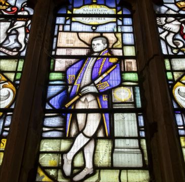 Stained glass window featuring a historical figure in 18th-century attire.