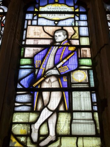 Stained glass window featuring a historical figure in 18th-century attire.