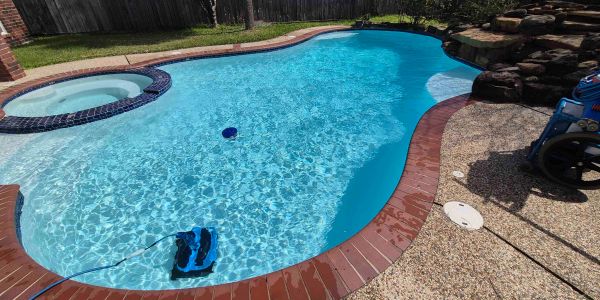 A clean backyard swimming pool with a hot tub.