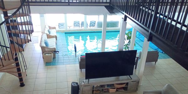 Indoor pool with seating and TV in a spacious home.