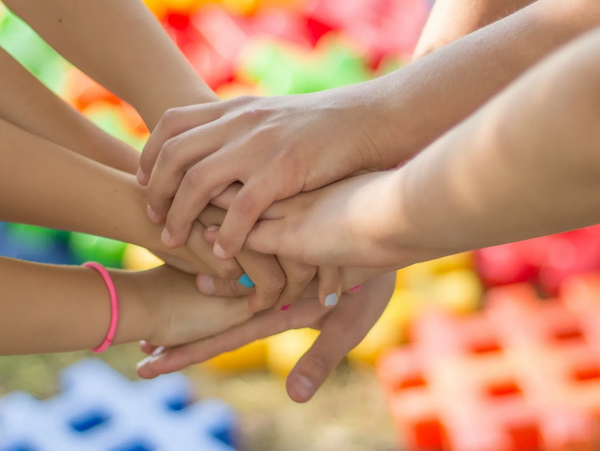 Hands of children stacked together showing teamwork and unity.