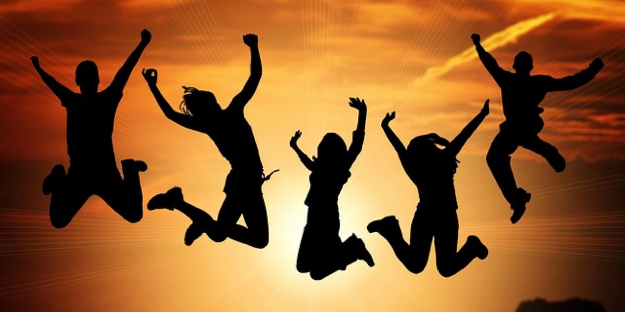 Silhouettes of five people joyfully jumping against a vibrant sunset.