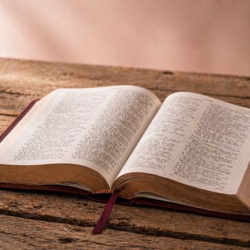 An open Bible resting on a rustic wooden table.