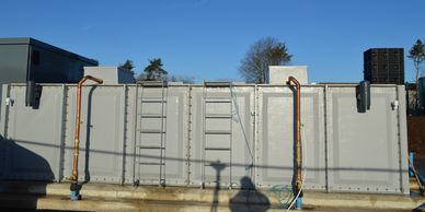 Sectional GRP cold water storage tank installed with external pipework.