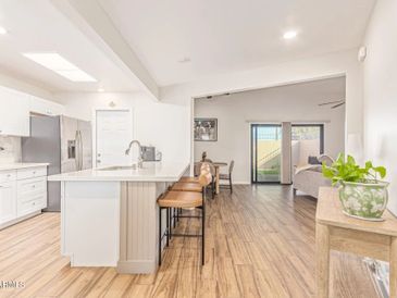 Bright modern kitchen with wooden flooring and bar stools.