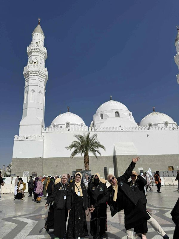 Group of women posing happily at a mosque courtyard.