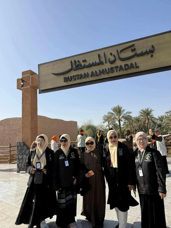 Group posing under Bustan Almustadal sign.