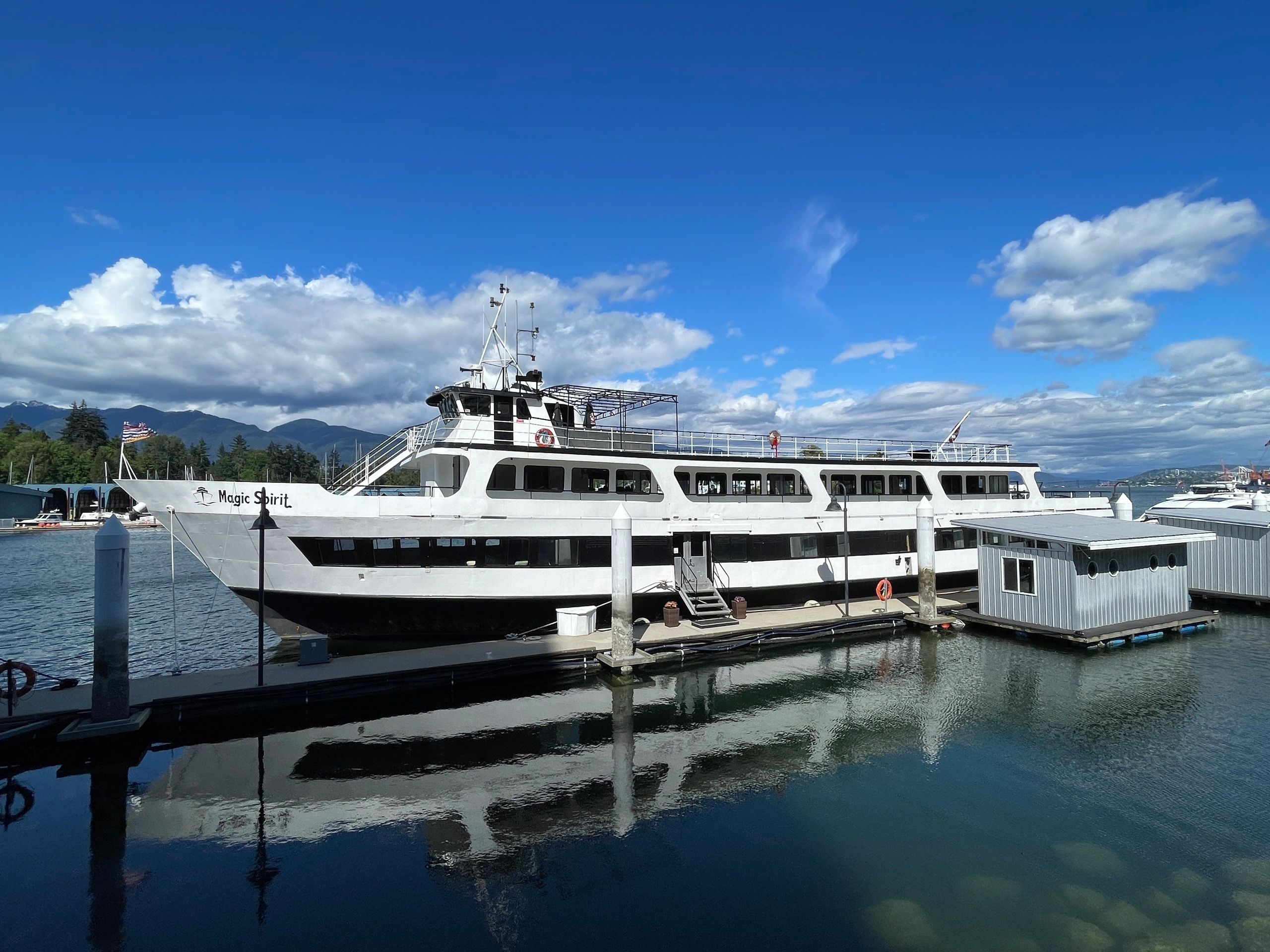 The Magic Spirit ferry docked by a calm waterfront under a clear blue sky.