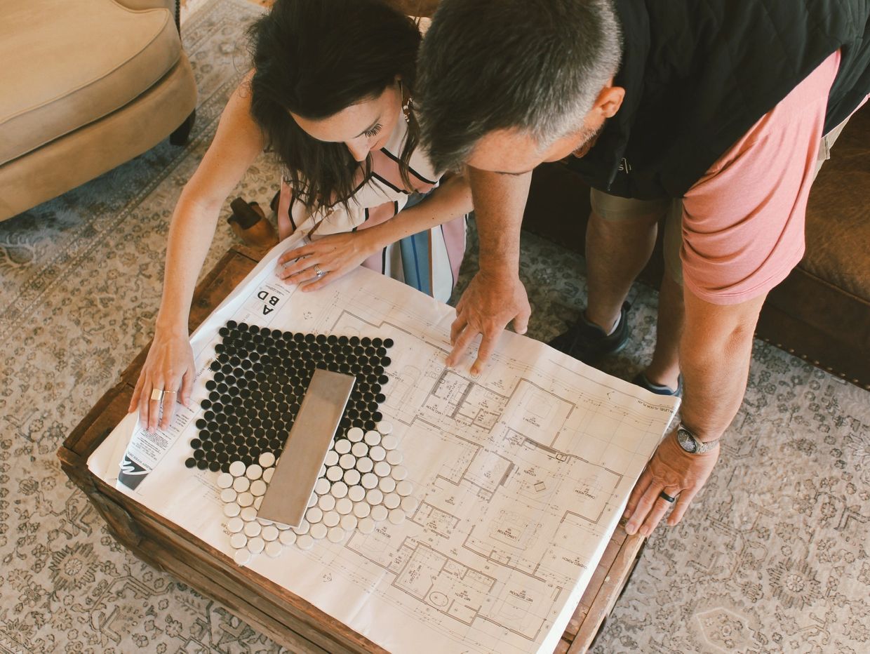 Couple examining home floor plan with tile samples.