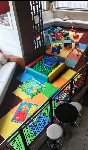 Colorful indoor play area with foam mats, ball pit, and toys for children.