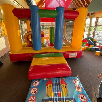 Colorful inflatable bounce house inside a play area with safety rules mat.