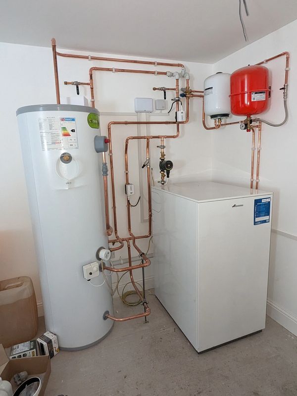Modern heating system setup with water tank and copper piping.
