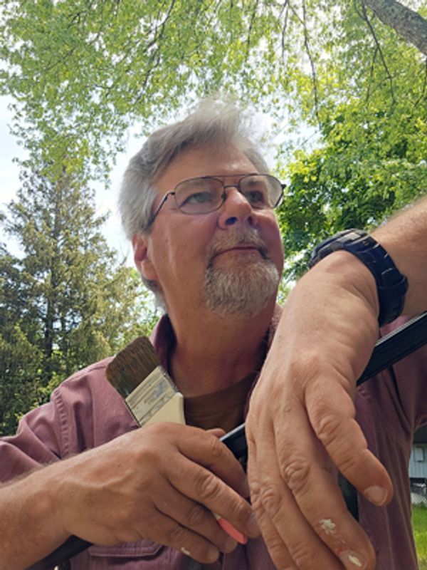 A man holding paintbrush and standing