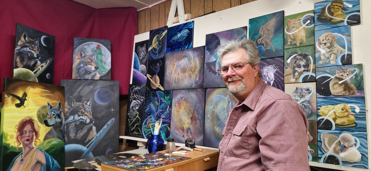 A man standing in between oil paintings