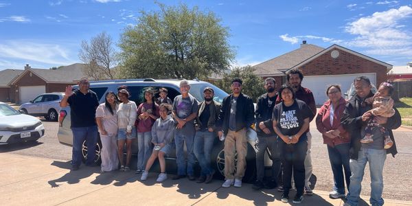 Group photo of diverse people outdoors on a sunny day.