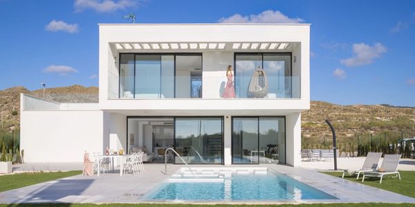 Modern white house with pool and mountain backdrop.