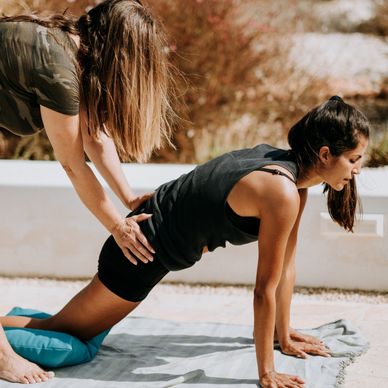 a personal trainer assisting someone to stretch. 