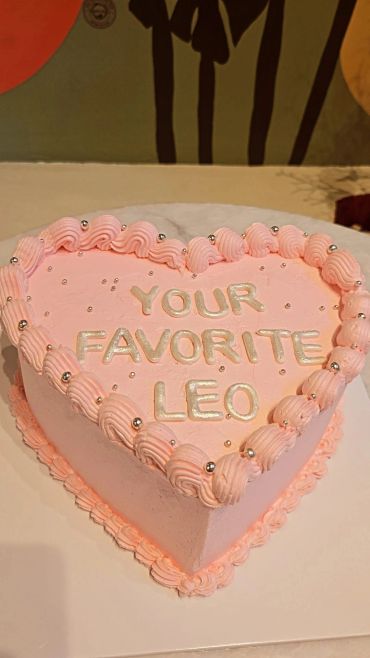 Pembe kalp şeklinde "YOUR FAVORITE LEO" yazılı pasta.