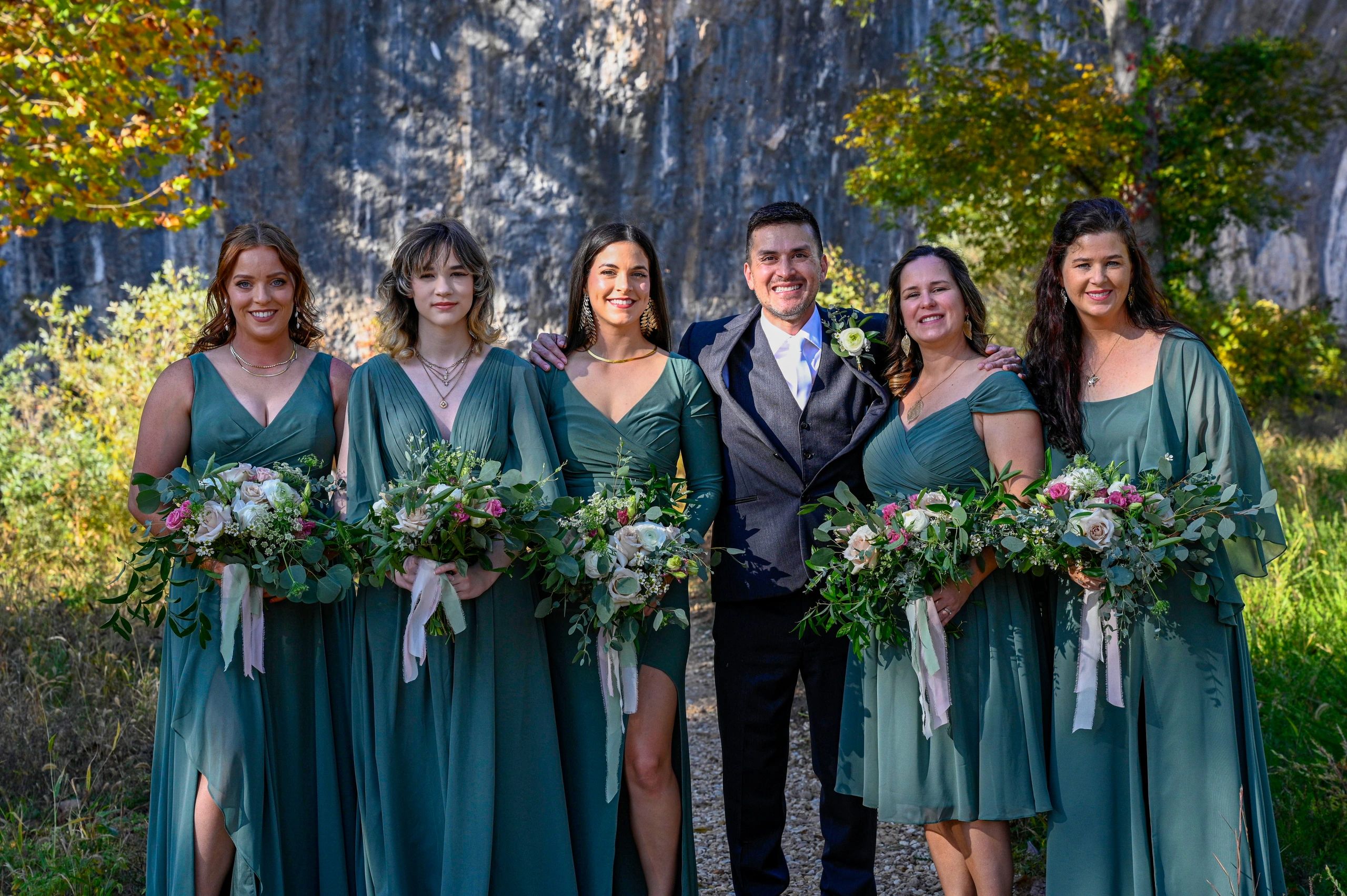 Bridemaids and groom holding garden bouquets in shades of pink, blush and sage greens. 