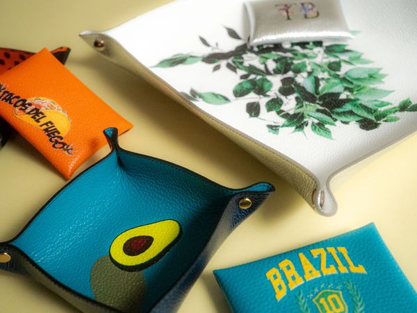 Colorful leather trays with various designs and logos.