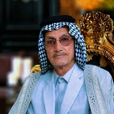 Äldre man i traditionell arabisk klädsel sitter på en guldfärgad stol.