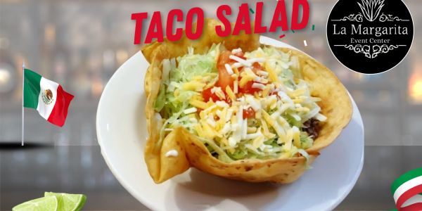 A colorful taco salad with cheese, lettuce, and tomato in a crispy shell.