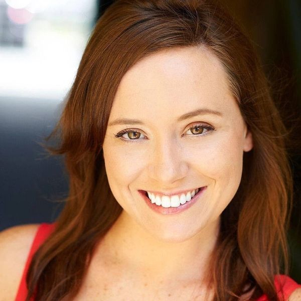 Close-up of a smiling woman with reddish-brown hair and green eyes.