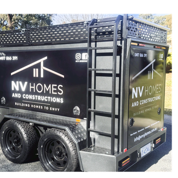 Black trailer with NV Homes advertisement and ladder.
