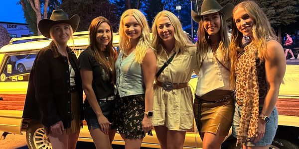 Group of six women posing together outdoors at night.