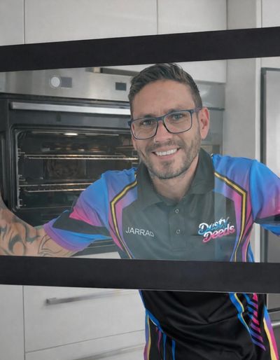 Man smiling through a microwave window in a colorful shirt.