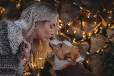 A woman sharing a tender moment with her dog amid cozy, warm lights.