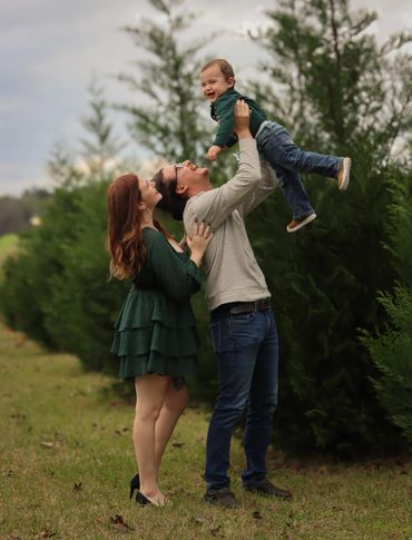 A joyful family moment outdoors with parents lifting their smiling child.
