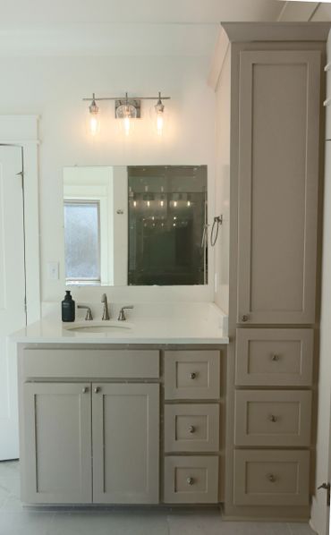 Minimalist bathroom vanity with beige cabinets, white countertop, and modern light fixture.