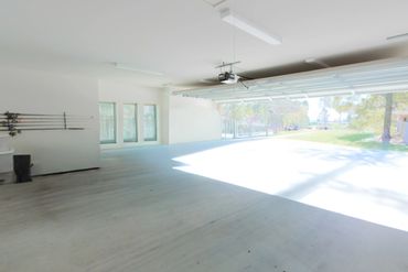Empty spacious garage with open door and fishing rods on the wall.