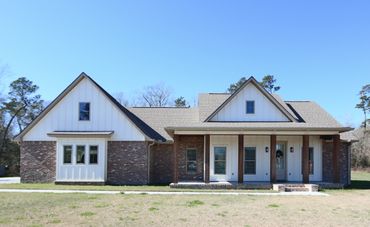 Modern farmhouse with brick and white siding under a clear blue sky.
