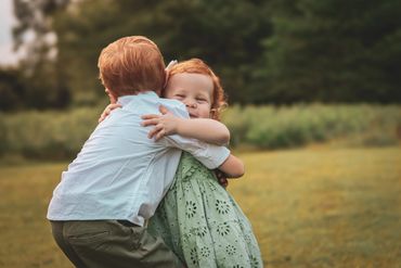 Two children embracing each other outdoors with joy.