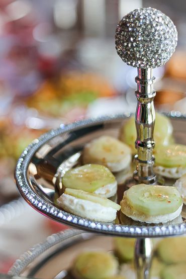 Elegant silver tiered tray with cucumber-topped canapés.
