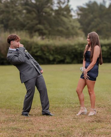 Young couple posing playfully outdoors in formal attire.