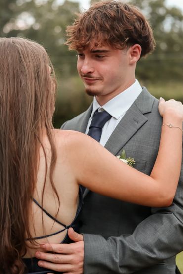 Young couple dancing closely outdoors, dressed formally.