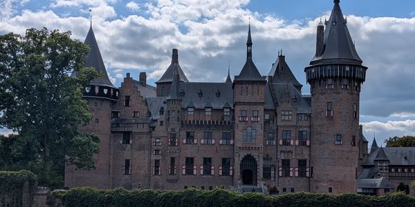 A historic castle with multiple towers under a partly cloudy sky.