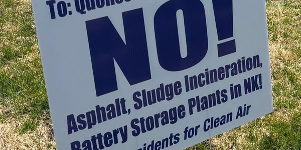 Protest sign opposing asphalt, sludge incineration, and battery storage plants in a community.