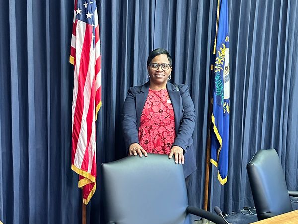 Woman standing behind a chair between two flags.