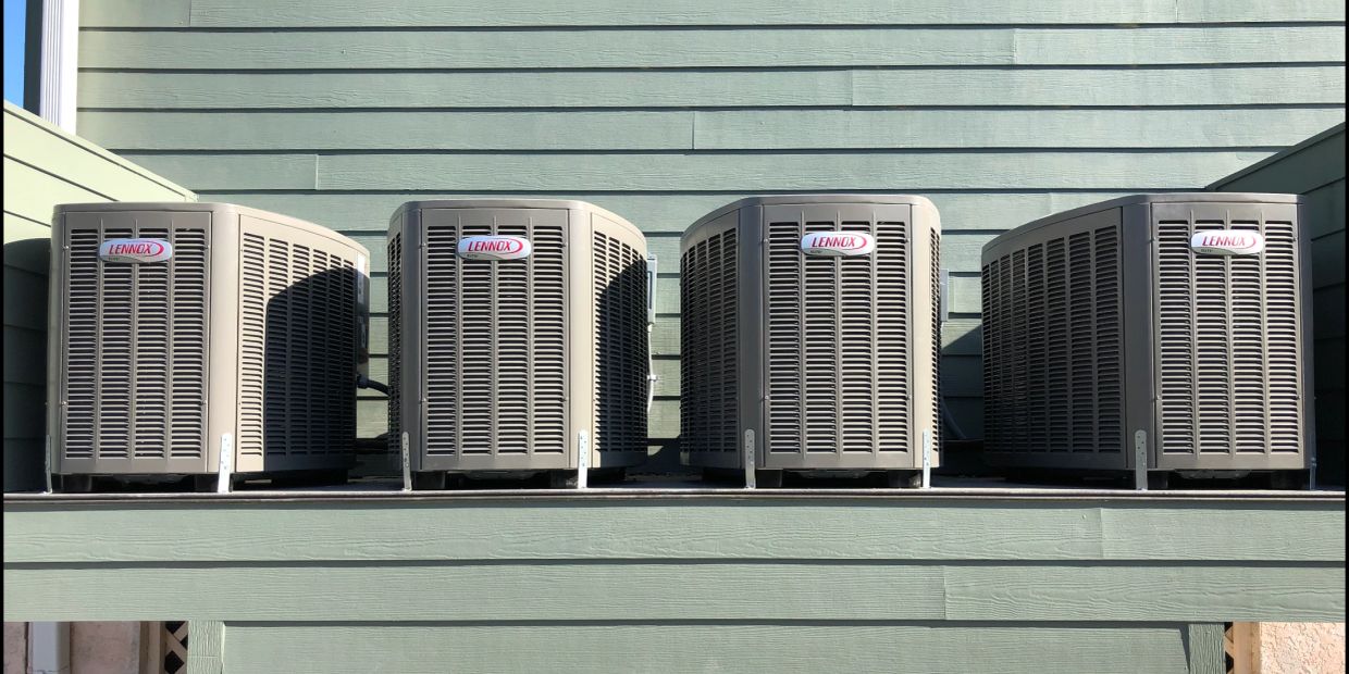 Four Lennox air conditioning units lined up outdoors.