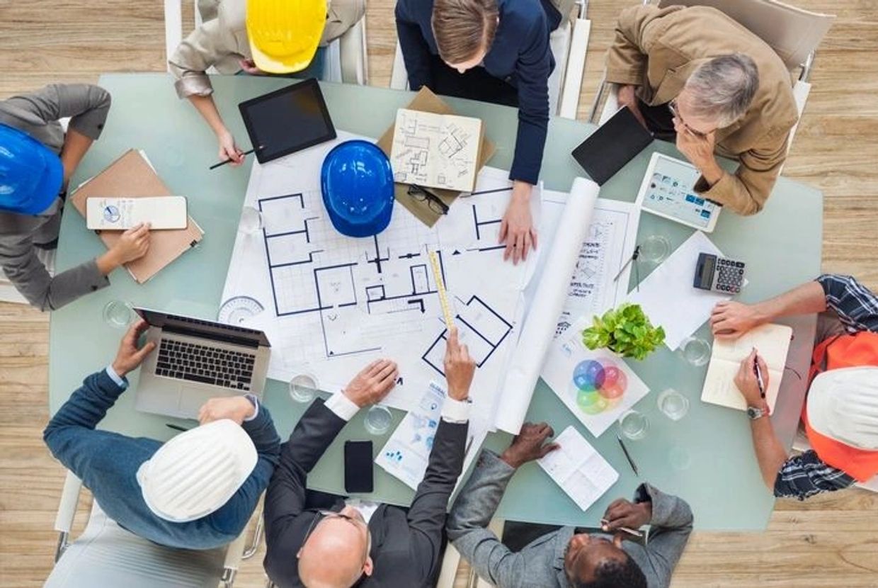 Team of architects and engineers discussing building plans at a table.