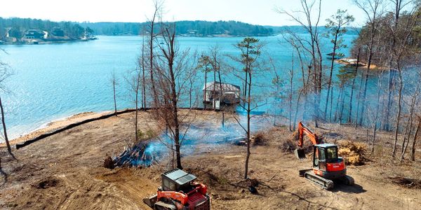 Clearing land near a lake with construction machinery.
