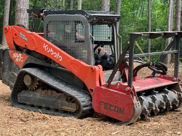 Kubota excavator with Fecon attachment in a forest.