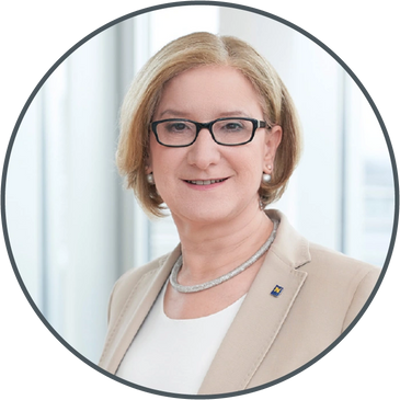Professional woman in business attire with glasses, smiling.