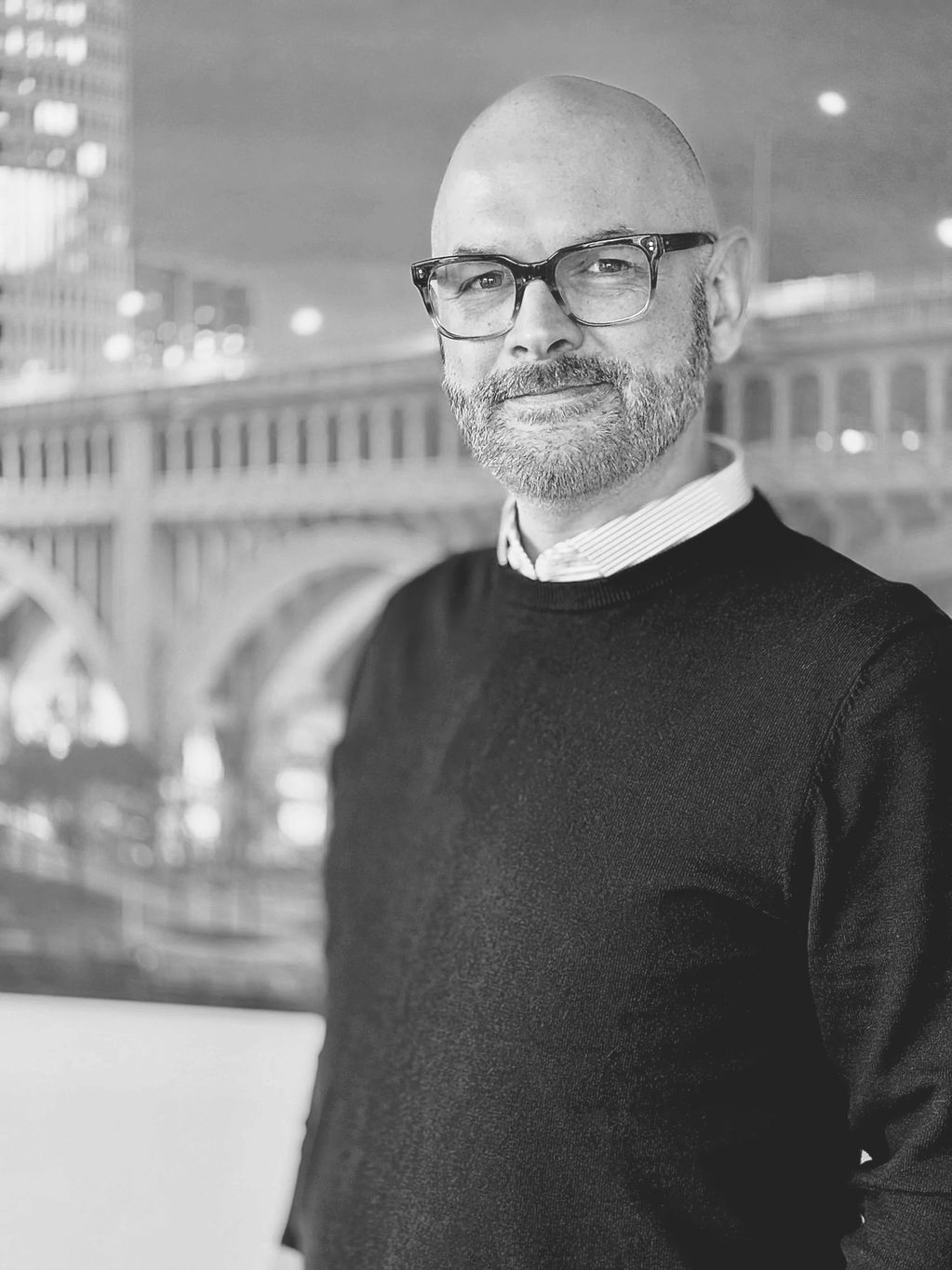 Smiling man with glasses and beard in a sweater.